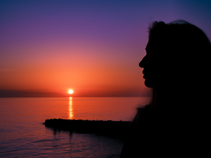 The silhouette of a girl against the backdrop of a beautiful sea sunset