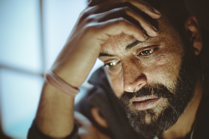 Sad mid adult man thinking at home.