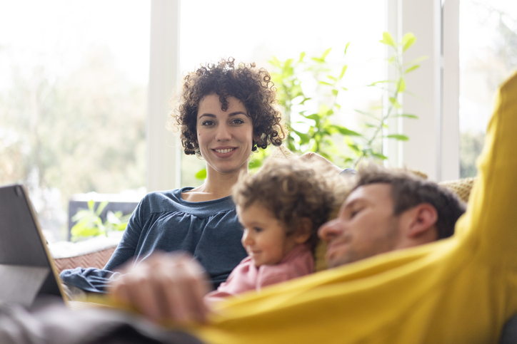 Family lying on couch watching movie on theit tablet