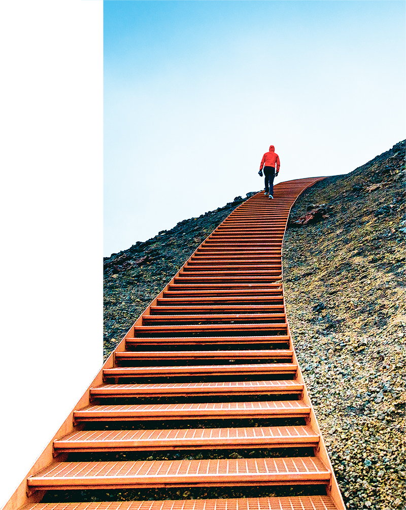 Man Walking on Stairs on a Mountain Against Blue Sky