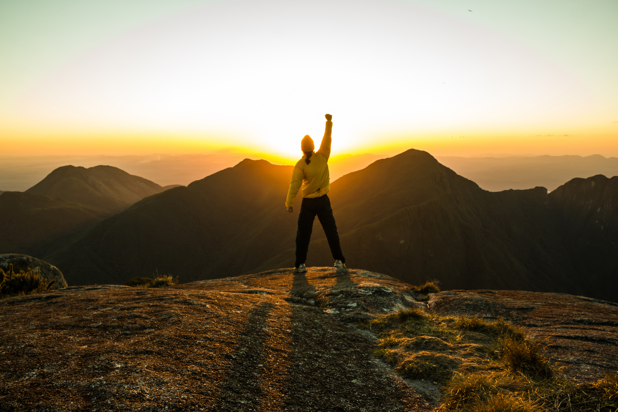 Man celebrating success on top of a mountain