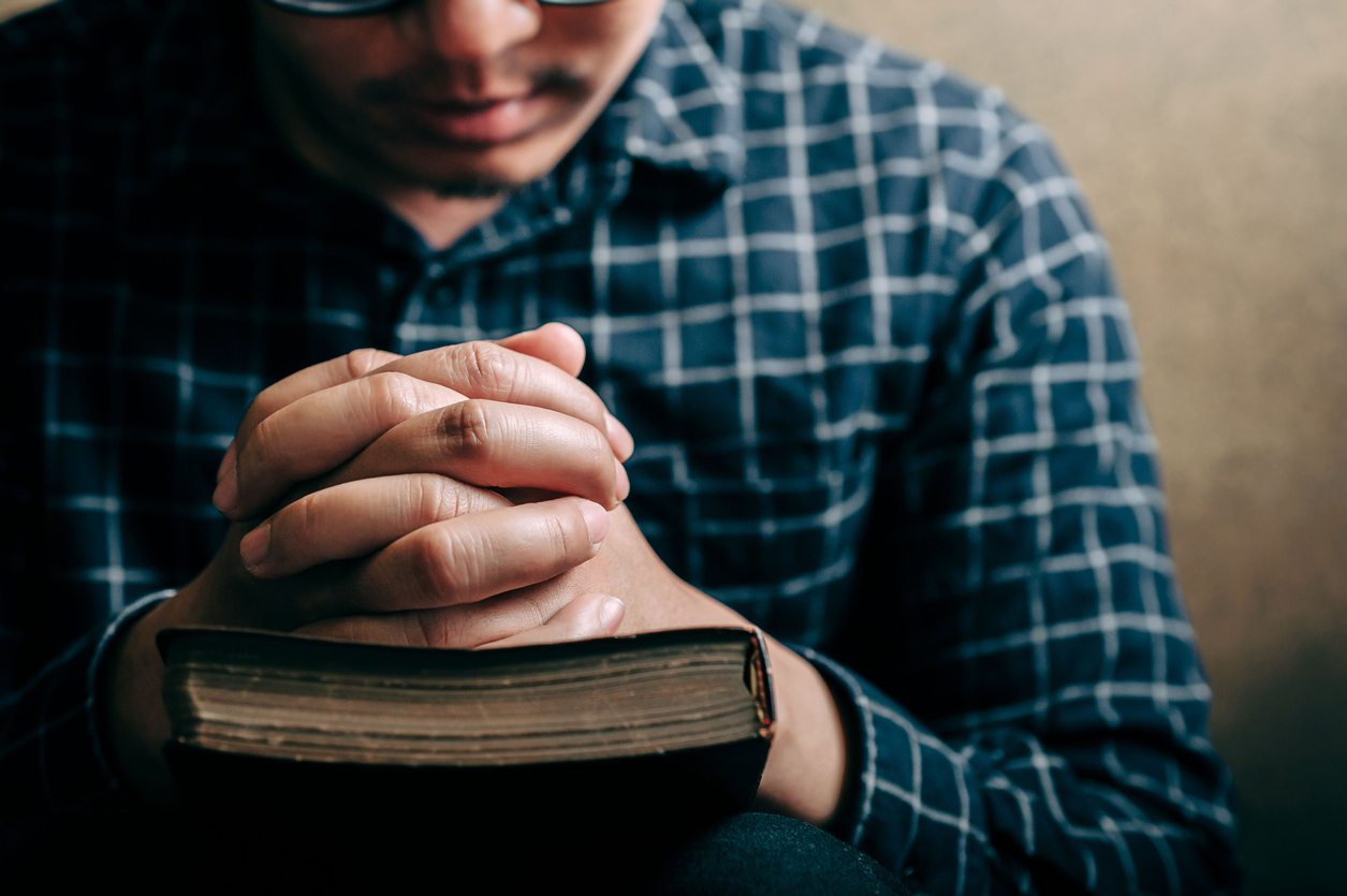 Christian life crisis prayer to god. Man Pray for god blessing to wishing have a better life. man hands praying to god with the bible. believe in goodness. Holding hands in prayer, eyes closed.