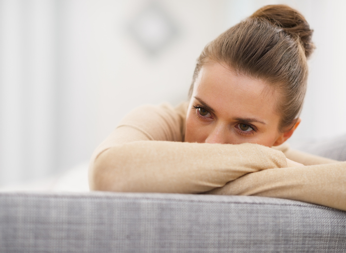 stressed young woman sitting on sofa