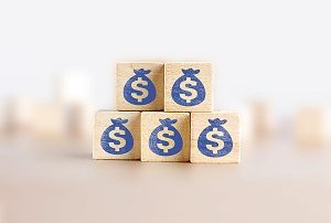 Business growth, increase profit, increase income or saving concept. Wooden blocks with the US Dollar symbol arranged in pyramid staircase and a man is holding the top one.