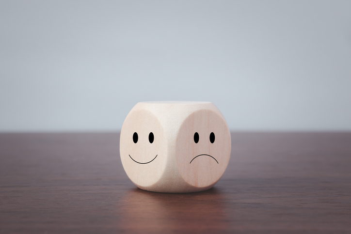 Smiling and sad symbols on wooden blocks on a gray background