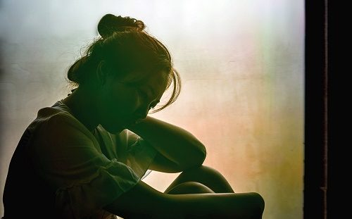 Vintage filtered on silhouette of depressed girl sitting on the window