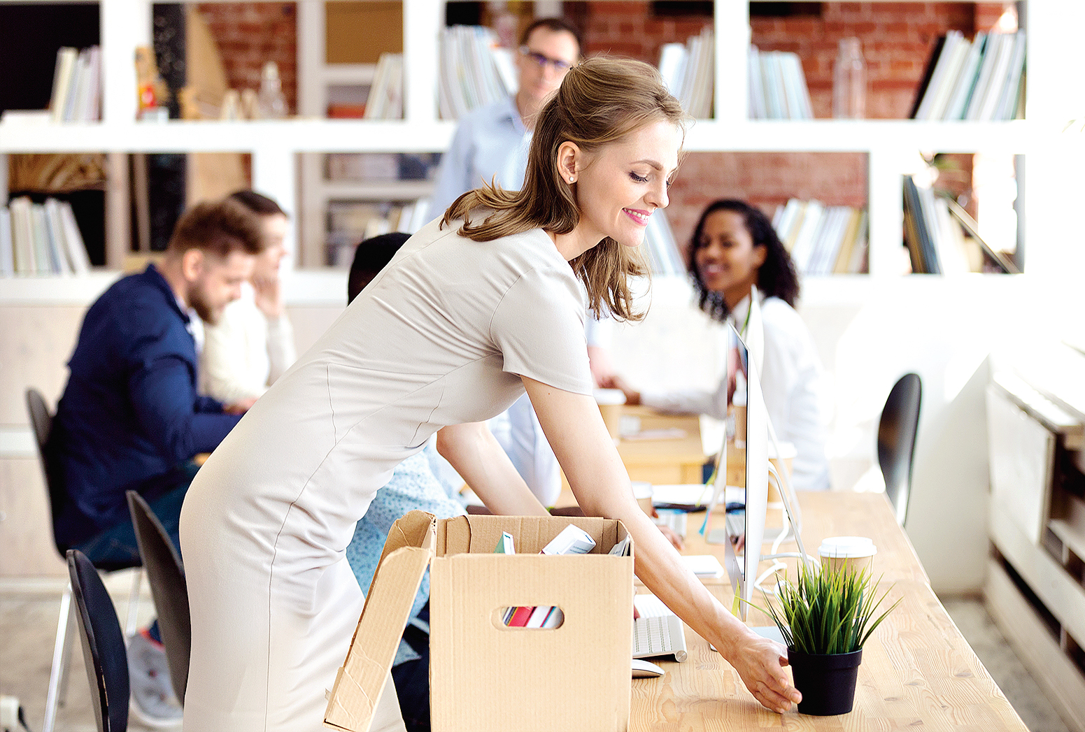 Happy new employee unpacking box with personal belongings in office