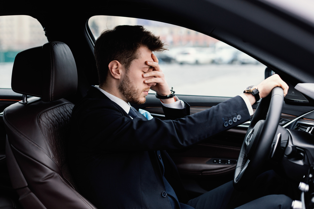 Sad businessman driving alone in his new car