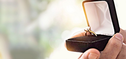 Close up of mans hand holding open box with engagement ring