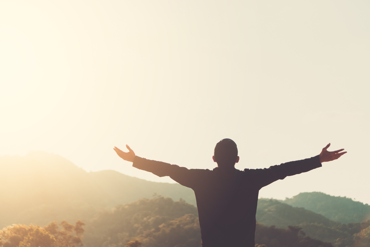 Copy space of silhouette man raise hand up on top of mountain and sunset sky cloud abstract background