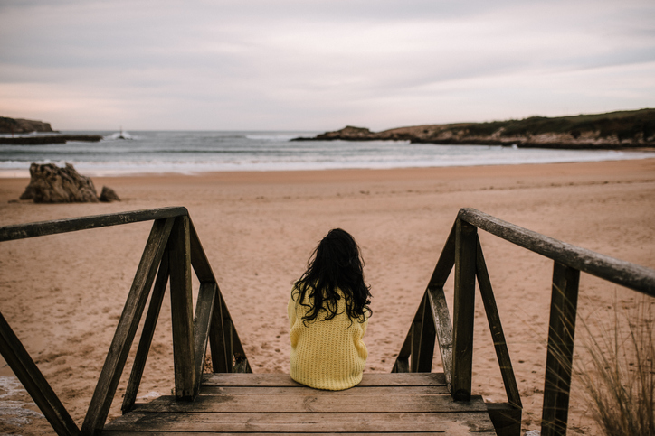 Rear view of woman sitting by a beach