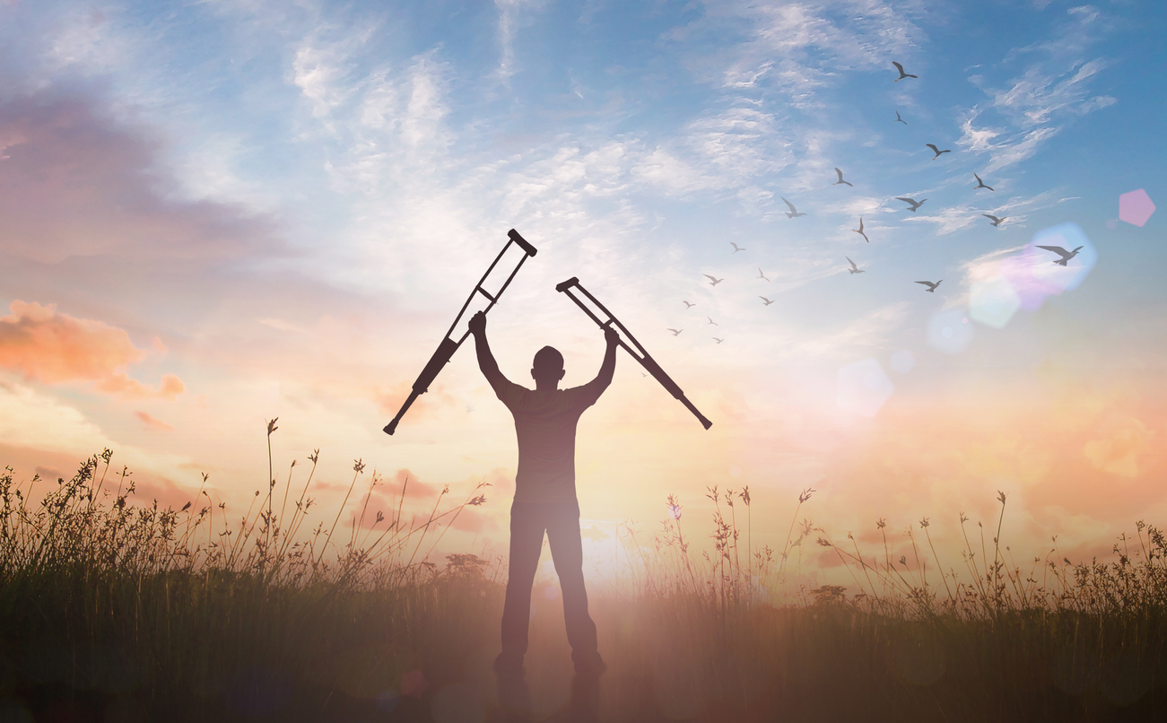 Disabled man standing up and raising his crutches