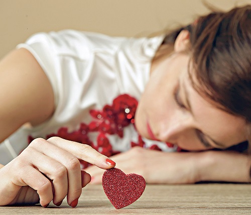 Sad lonely woman holding red heart.  Being alone on Valentine&#8217;s day. Heartbreak, divorce or breakup concept.