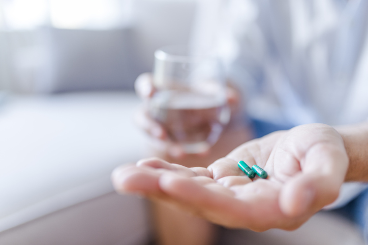 Man takes medicines with glass of water.