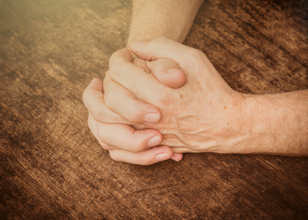 praying hands on wooden table, vintage color