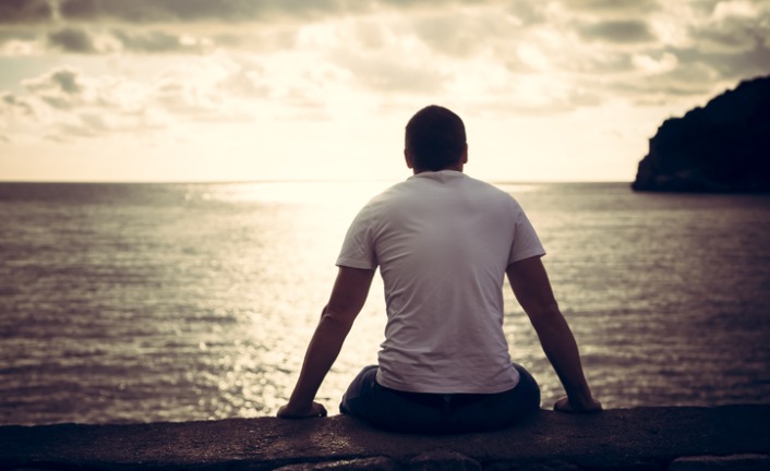 lonely-man-looking-with-hope-at-horizon-with-sunlight-during-sunset-picture-id642792008