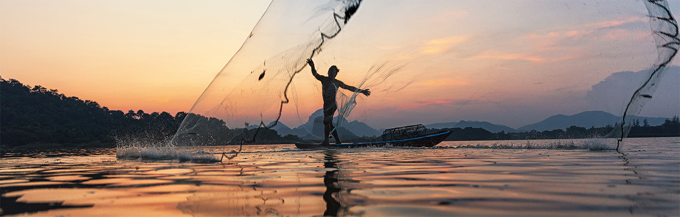 Asian fishermen throwing fishing net during twilight on wooden boat at the lake. Concept Fisherman&#8217;s Lifestyle in countryside. Lopburi, Thailand, Asia
