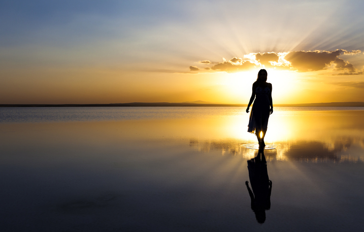 Young woman walking on water at sunset