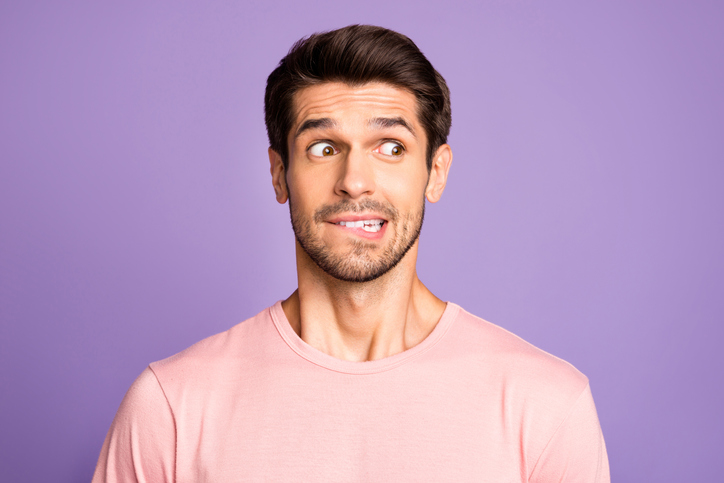 Close-up portrait of his he nice attractive funny confused brunet bearded guy wearing pink tshirt waiting news biting lip isolated over violet purple lilac pastel color background
