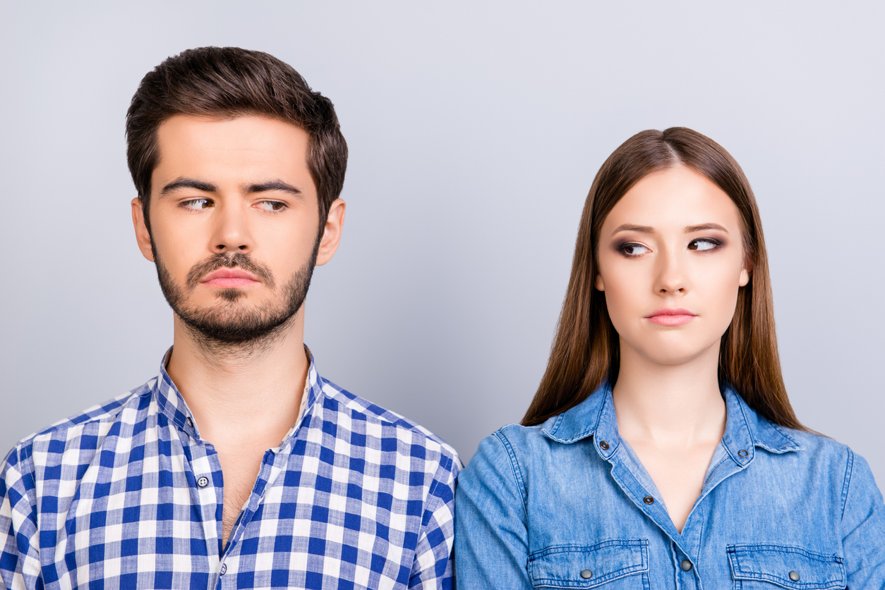 Mistrust and cheat problems. Annoyed couple is ignoring each other, but spy each other secretly, they stand on pure background in casual shirts