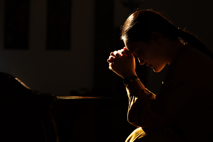 depressed women sitting in the low light church and praying, International Human Rights day concept