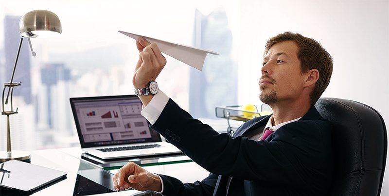 Bored White Collar Worker Throwing Paper Airplane In Office