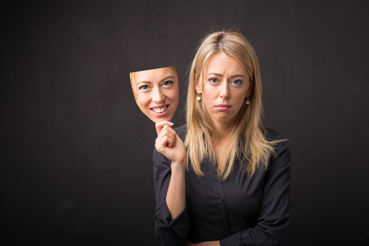 Woman holding mask of her happy face