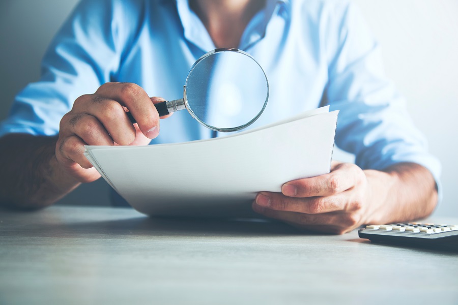 Businessman,Looking,Through,A,Magnifying,Glass,To,Documents