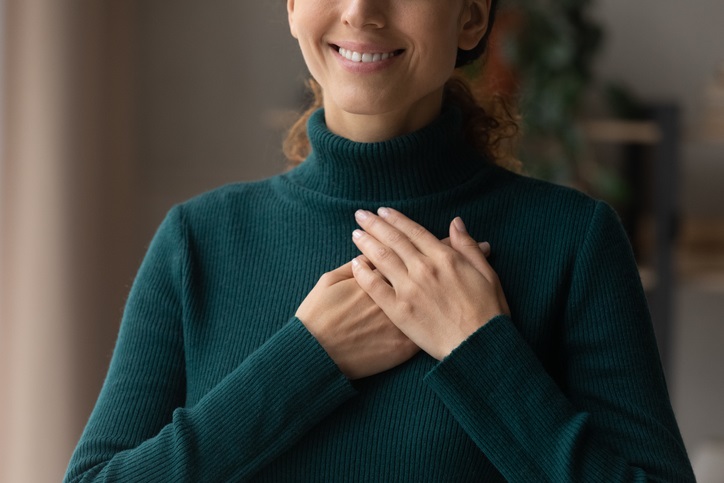 Cropped close up smiling woman holding folded hands on chest