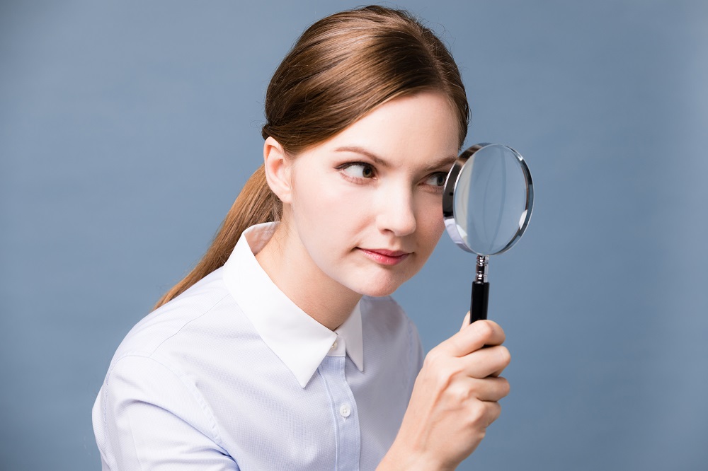 Young,Woman,Looking,At,Something,With,Magnifying,Glass.