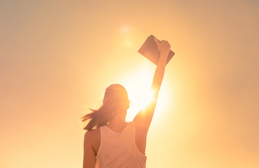 Winner. Woman holding bible in the sky.