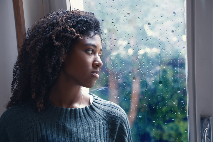 Young worried woman looking out of the window