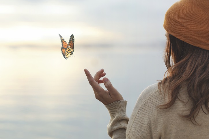 colorful butterfly is laying on a woman’s hand