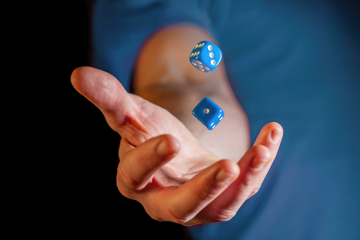 Caucasian male hand throwing blue dice cubes in the air &#8211; closeup with shallow focus