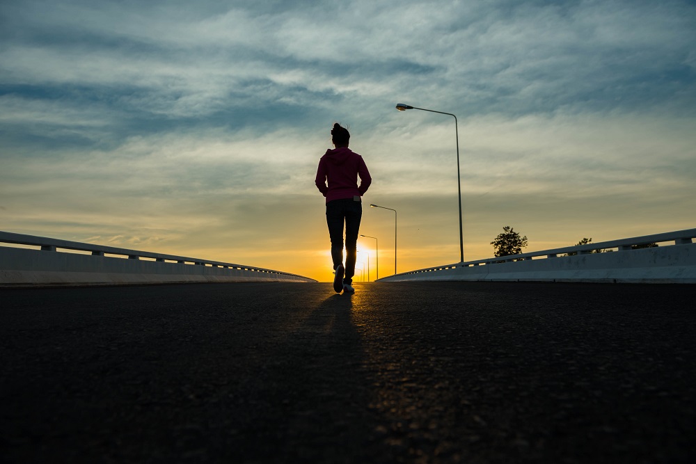 Silhouette,Woman,Walking,On,The,Street,At,Sunset.