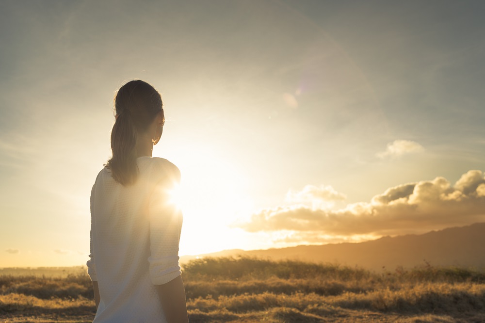 Female,Standing,On,Mountain,Looking,Towards,The,Beautiful,Sunset.