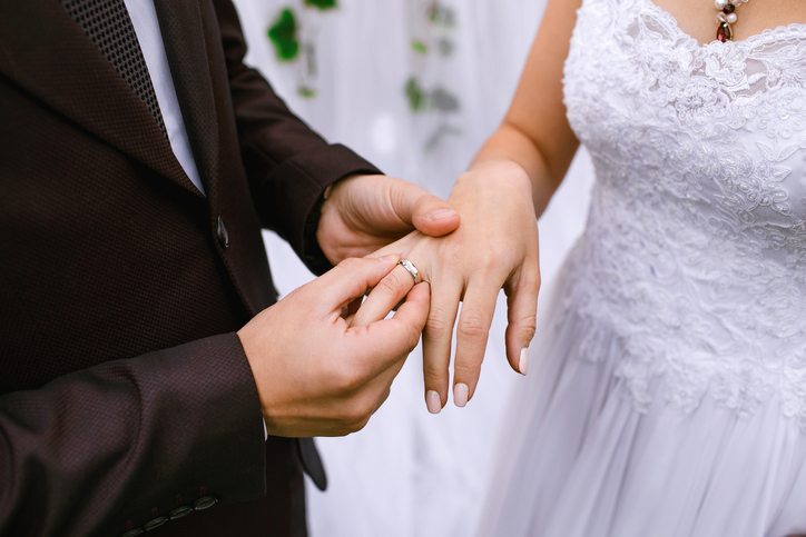 The groom proposes to his bride and puts the ring on his finger close-up. Wedding ceremony and happy bride and groom
