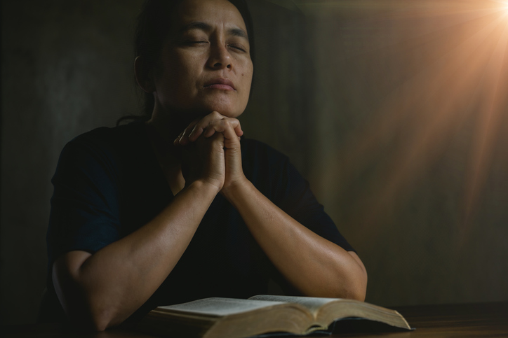 Prayer person hand in black background. Christian catholic woman are praying to god in dark at church. Girl believe and faith in jesus christ. Christ religion and christianity worship or pray concept.