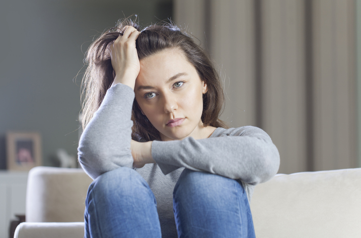 Depressed young woman on sofa at home