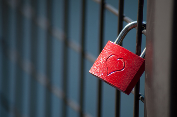 love padlock on metallic fence on blurred water background