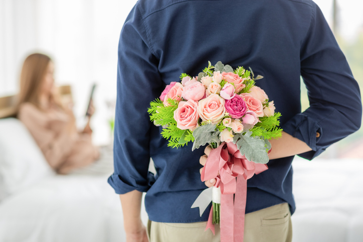 Man hiding flower at back.