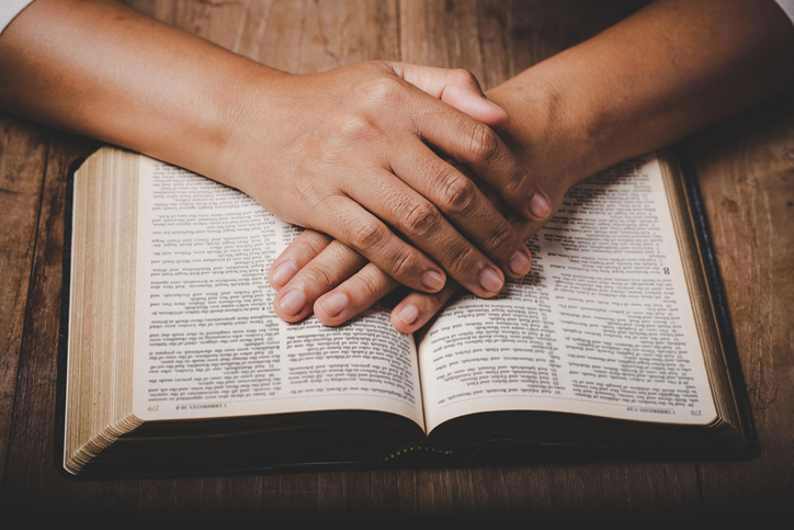 Close up of christian woman hand on holy bible pray and worship for thank god in church with black background, adult female person are reading book, concept for faith, spirituality and religion