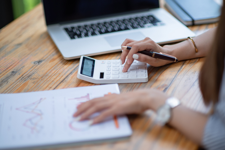 Close-up Of A Businessperson’s Hand Calculating Bill With Calculator