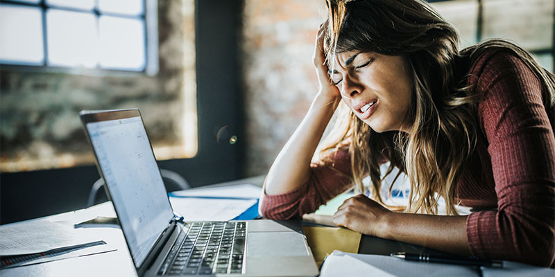 Frustrated woman working on a computer in the office.