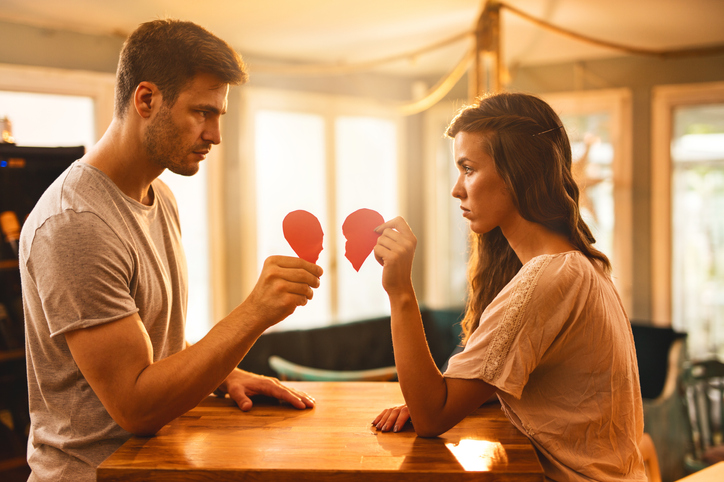 Young couple with broken heart shape looking at each other.