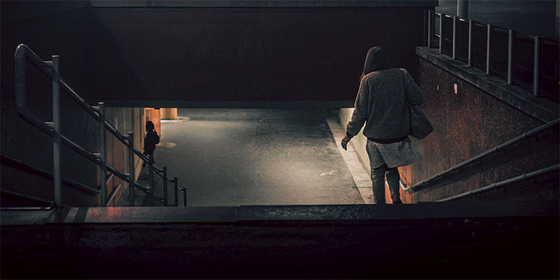 Person walking down a stairs to a subway at night