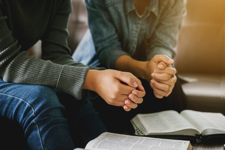 two women reading and study bible  in home and pray together.