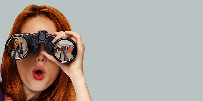 Teen redhead girl with binoculars isolated on white background