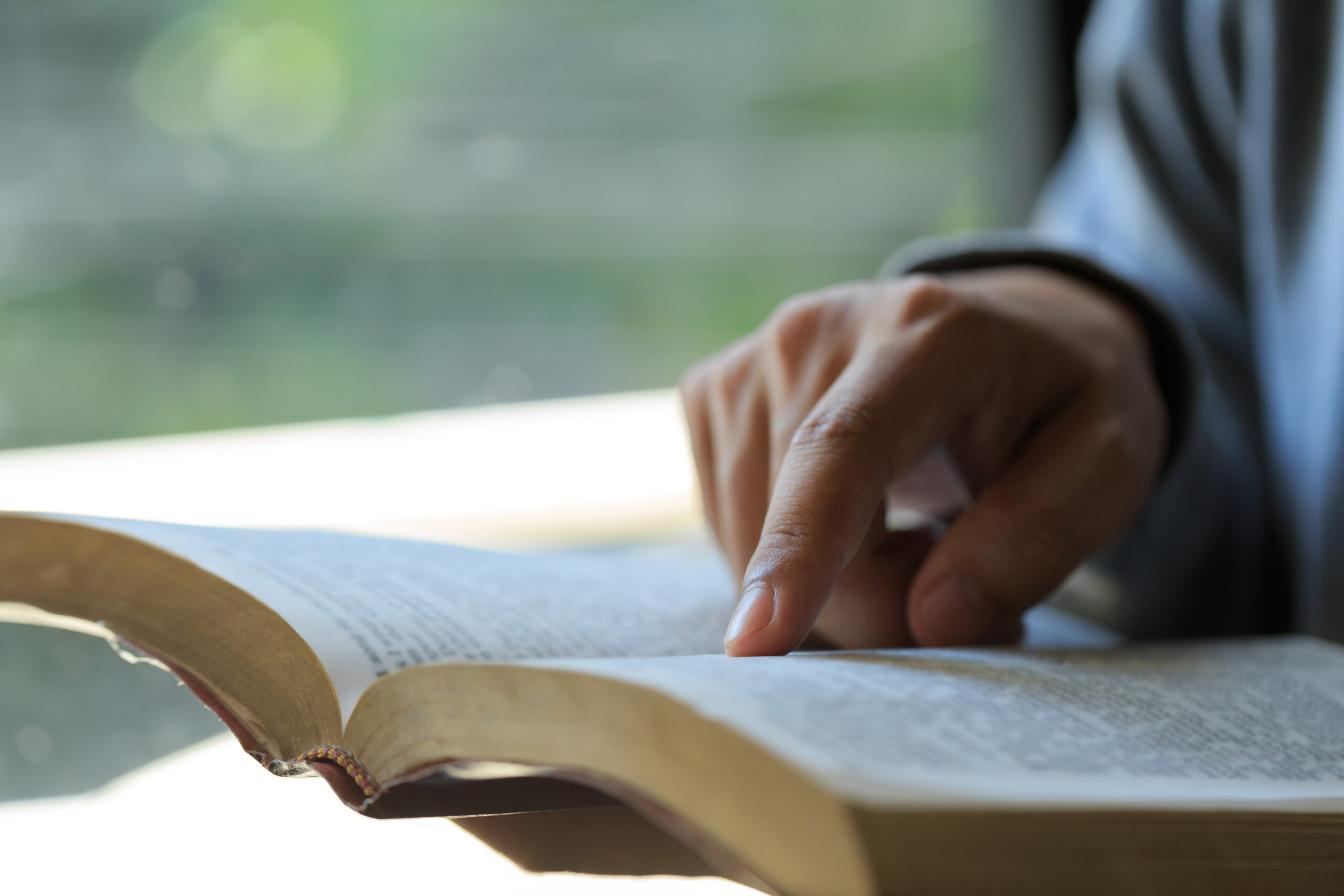 Close-up of Christian man&#8217;s hands while reading the Bible outside.Sunday readings, Bible education. spirituality and religion concept. Reading a book.