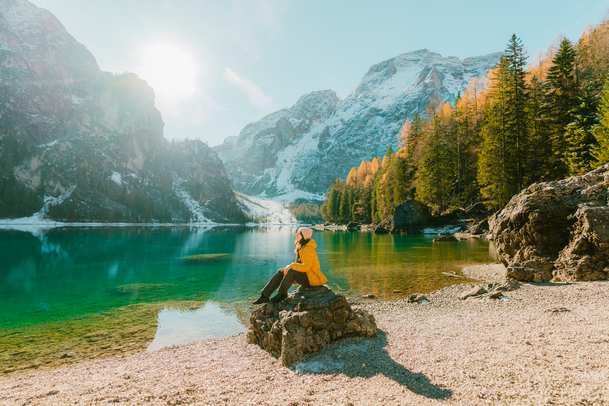 Woman  sitting on the background of  Lago di Braies in winter